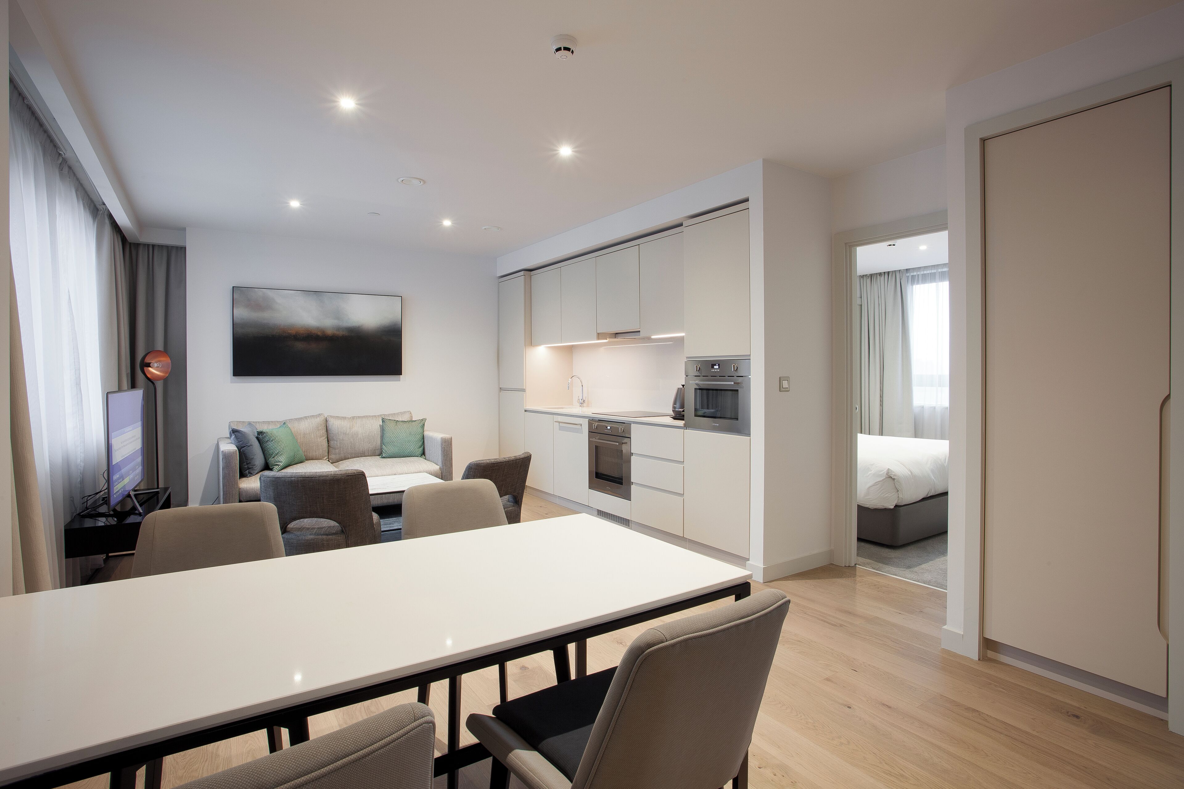 A modern apartment with a dining area, kitchenette, and a living space with a sofa and TV.