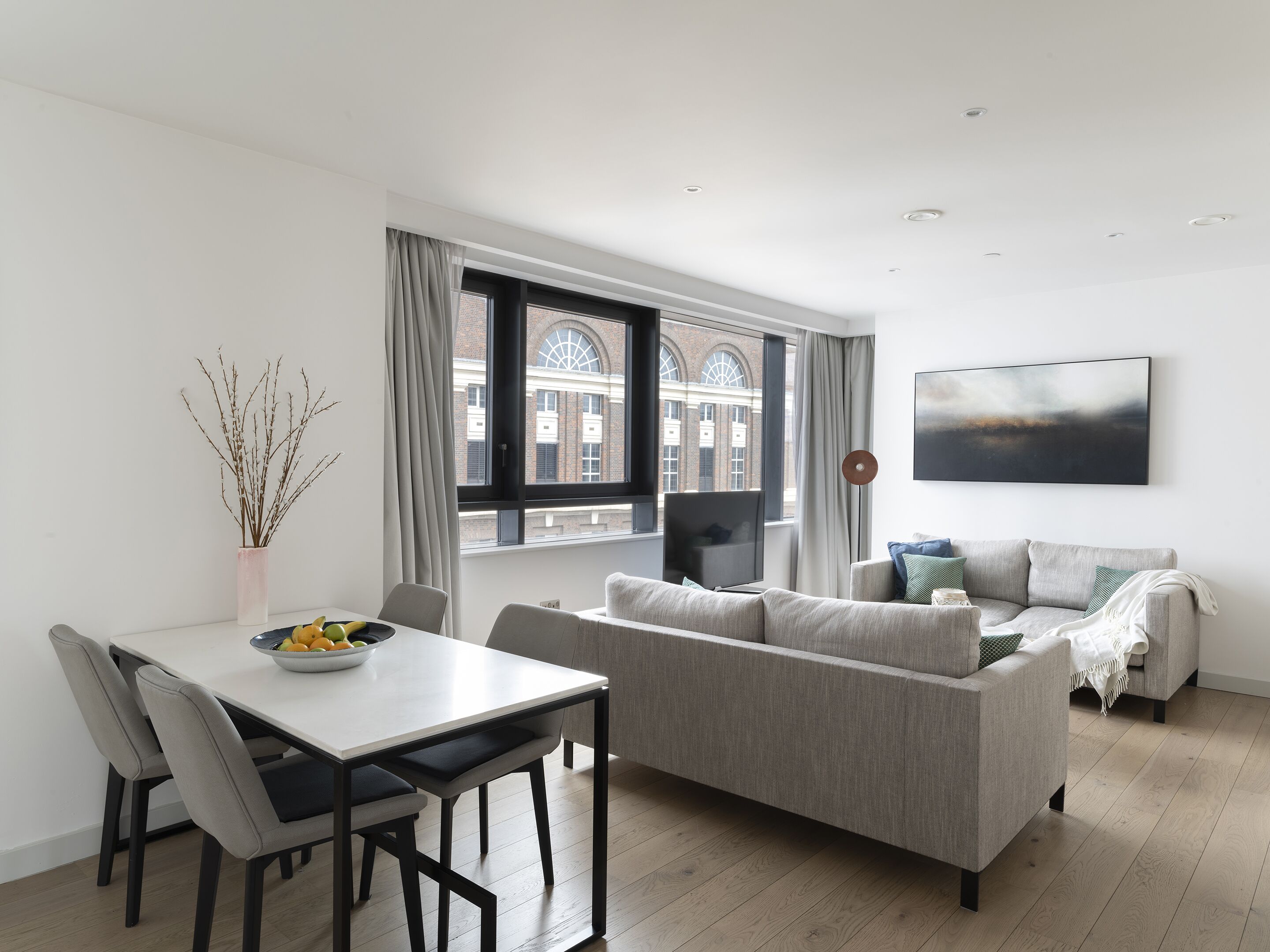 A modern living room with a dining table, grey sofa, and a TV.