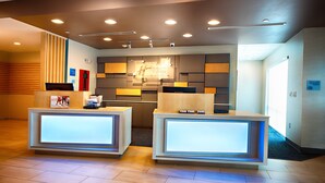 A hotel reception area with two reception desks, a modern design with recessed lighting, and a large mirror above the desks. - Holiday Inn Express & Suites Houston SW - Galleria Area by IHG (Houston)