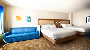 A hotel room with a large bed, a blue sofa, and a wooden floor. - Holiday Inn Express & Suites Houston SW - Galleria Area by IHG (Houston)