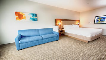 Ein Hotelzimmer mit einem blauen Sofa, einem Bett, einem Nachttisch und zwei Wandlampen.