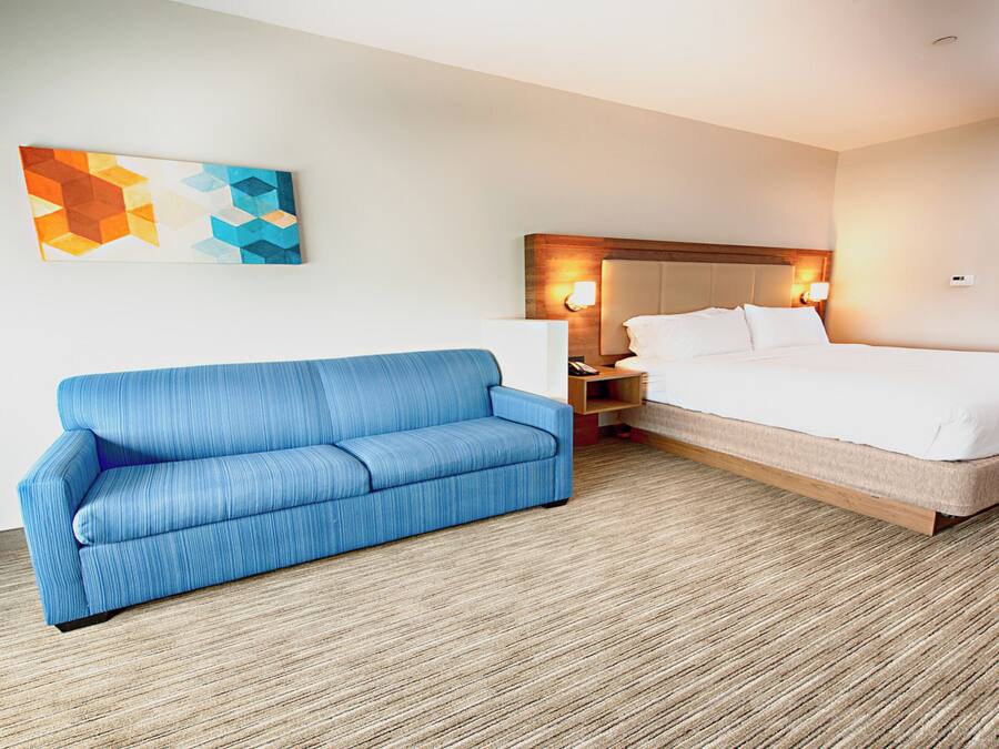 Ein Hotelzimmer mit einem blauen Sofa, einem Bett, einem Nachttisch und zwei Wandlampen.
