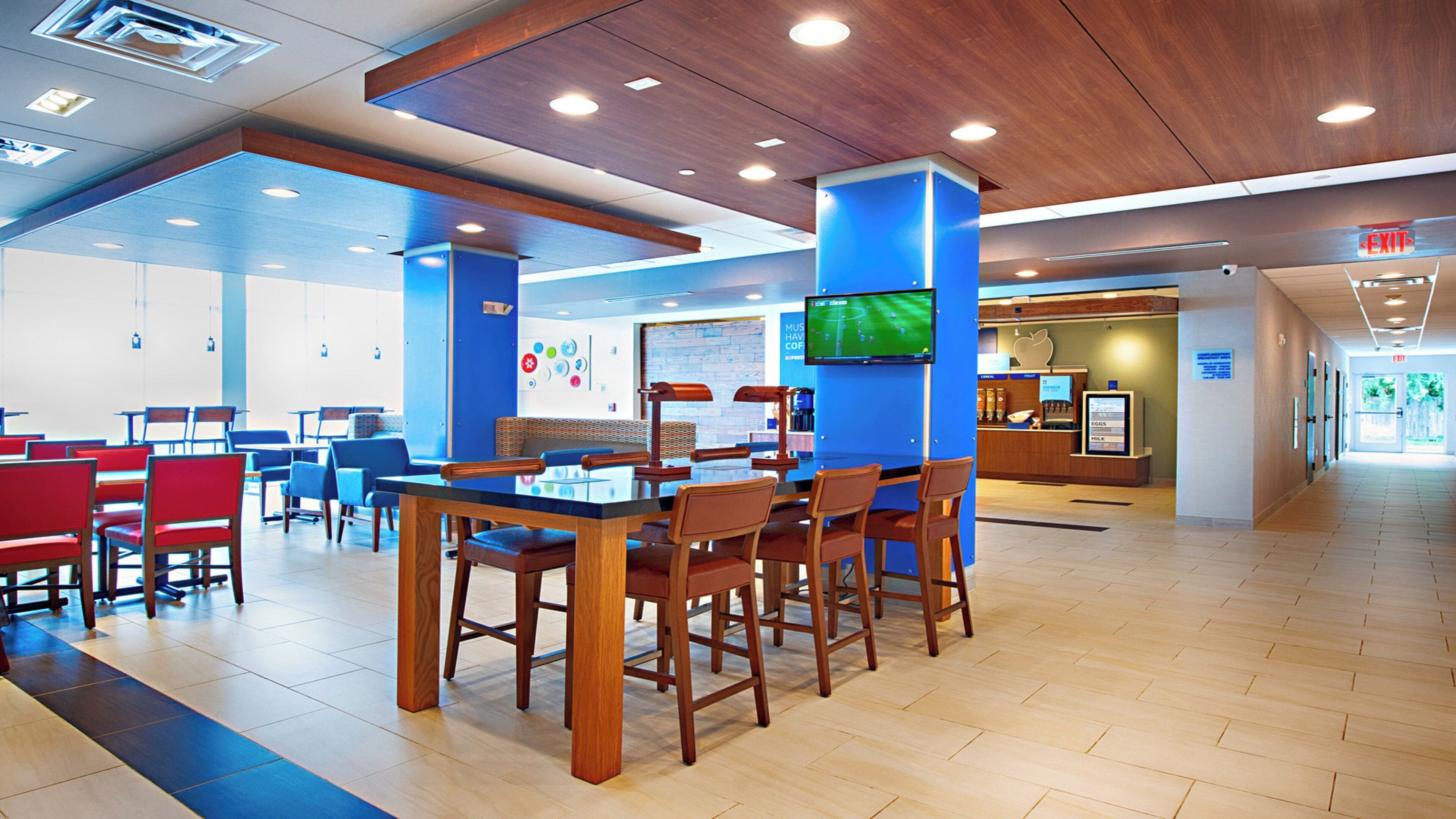 Una cafetería amplia con mesas y sillas de madera, una estación de café y un mostrador con menú.