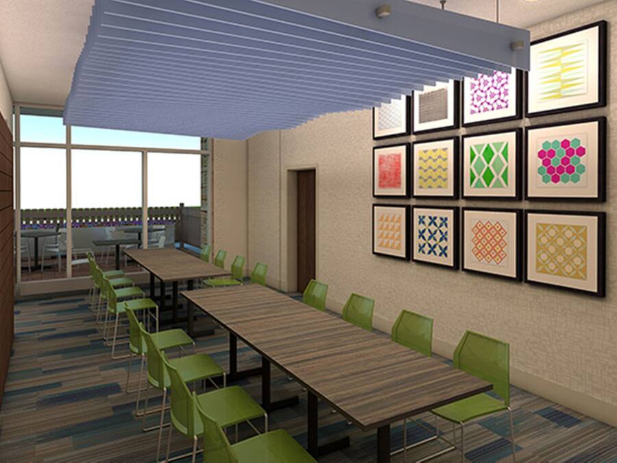Une salle de conférence avec une longue table, des chaises vertes et des motifs encadrés accrochés au mur.