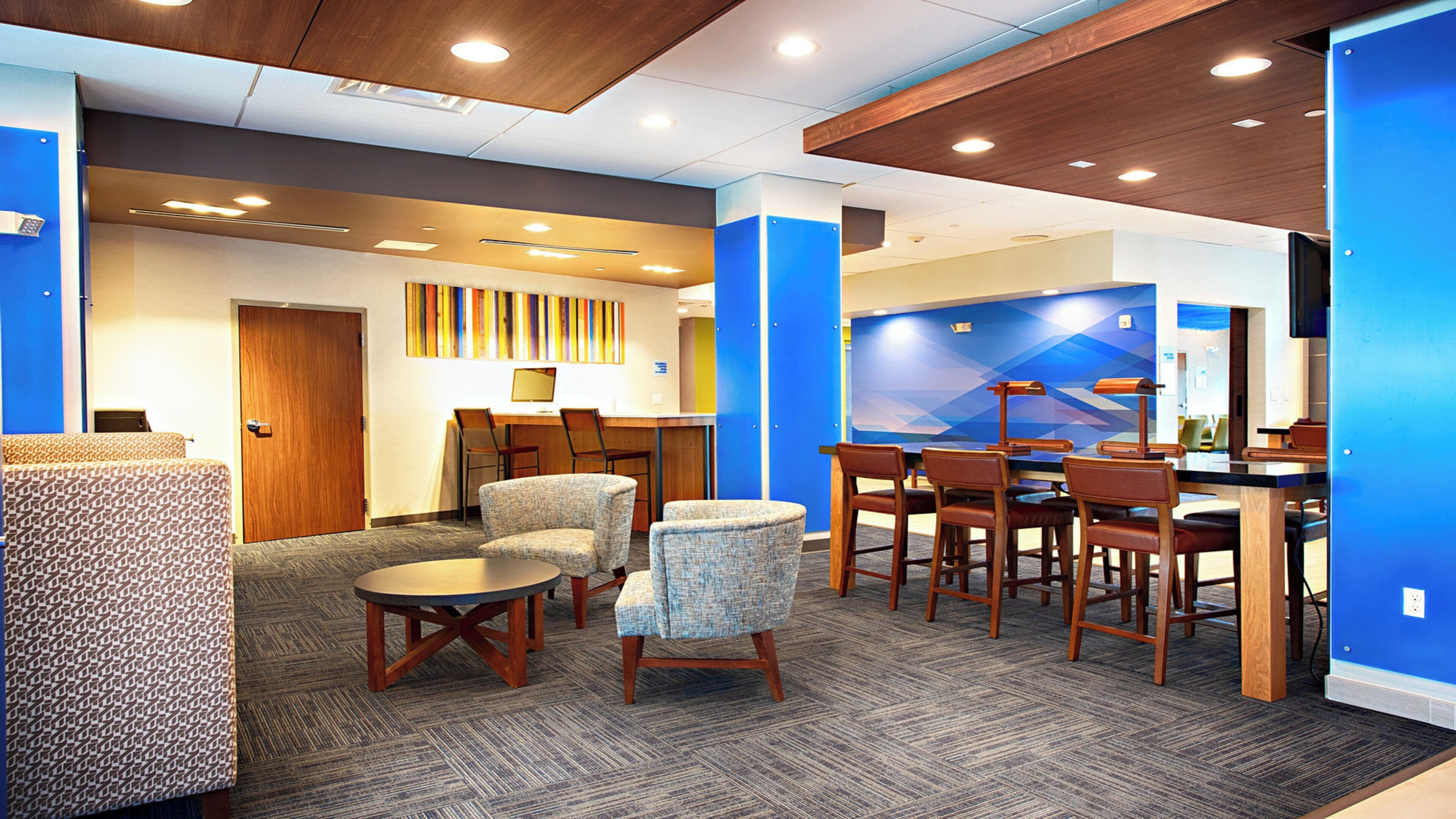 A hotel lobby with a reception desk, seating area, and a wall with a geometric pattern.