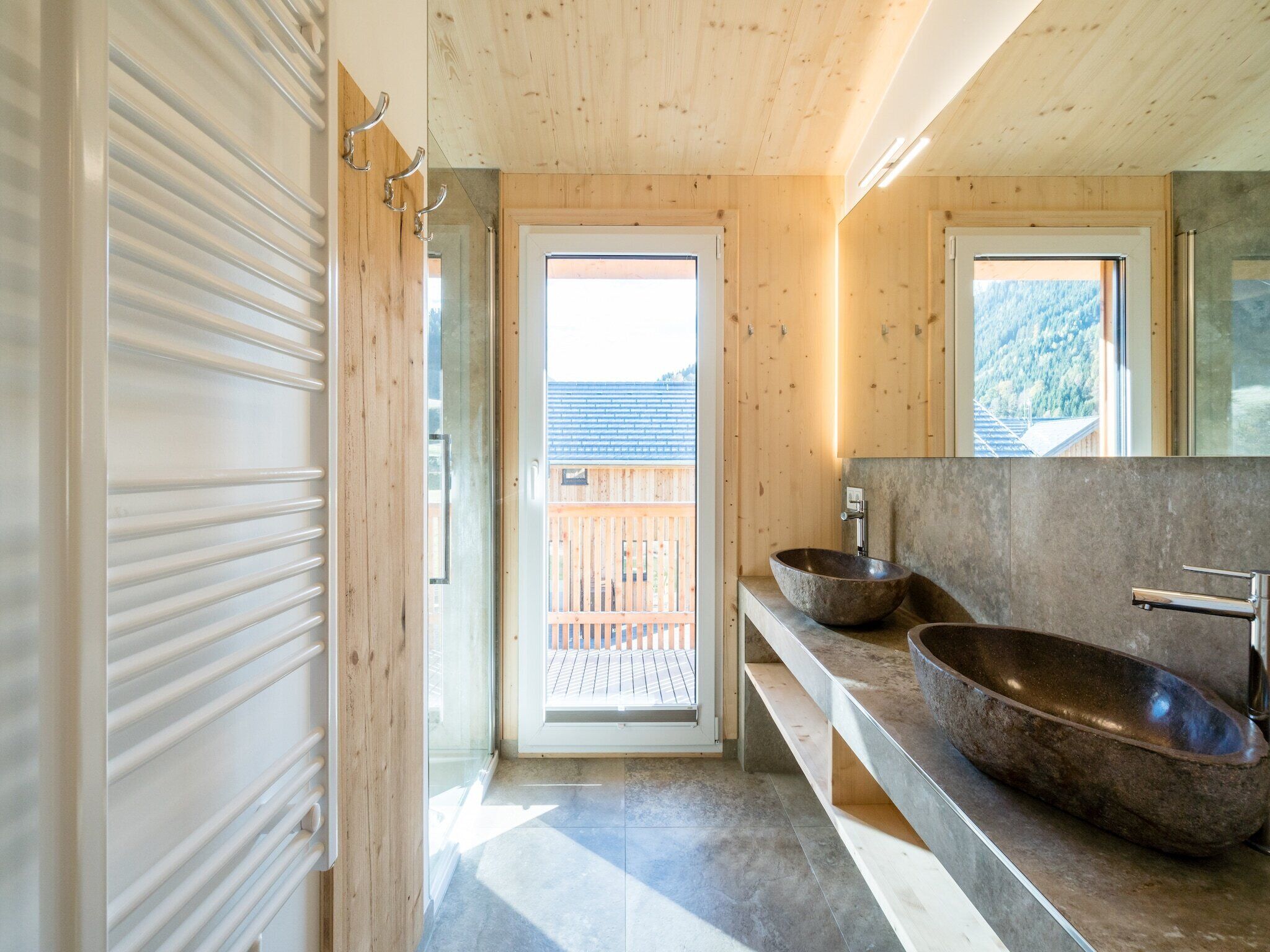 Une salle de bain moderne avec un intérieur en bois, une grande fenêtre et un lavabo en pierre.