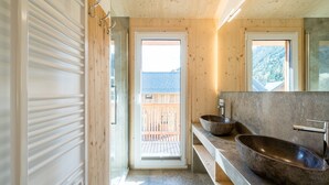 A modern bathroom with a wooden interior, a large window, and a stone sink. - Premium chalet with whirlpool (Murau)