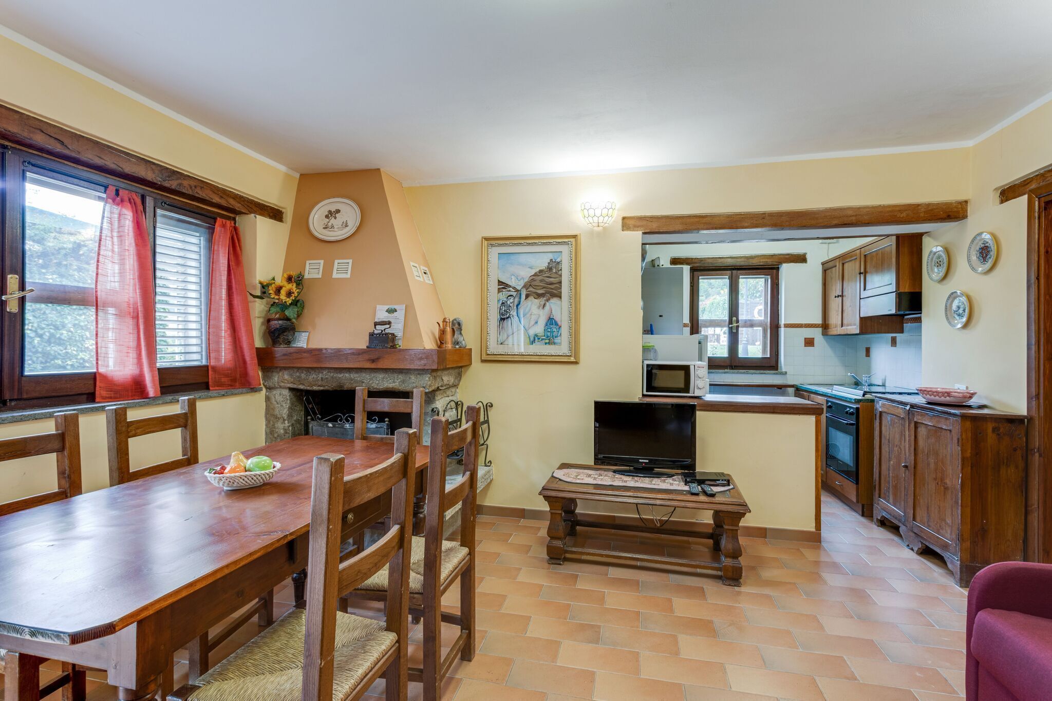 A cozy kitchen with a dining table, chairs, and a TV.