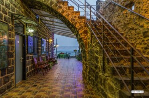 A stone-walled patio with outdoor seating and a view of the sea. - Villa Alliance (Tiberias)