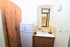 Una cocina compacta con un refrigerador blanco, armarios de madera, un lavamanos y una ventana con cortinas.