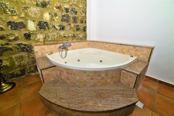 A bathroom with a freestanding bathtub, tiled walls, and a granite countertop. - Villa Alliance (Tiberias)