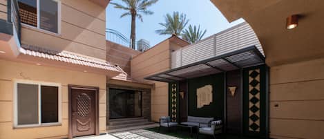 A modern building with a patio area, outdoor seating, and palm trees in the background.