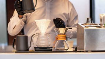 A coffee-making setup with a coffee maker, a glass carafe, and a kettle on a table.