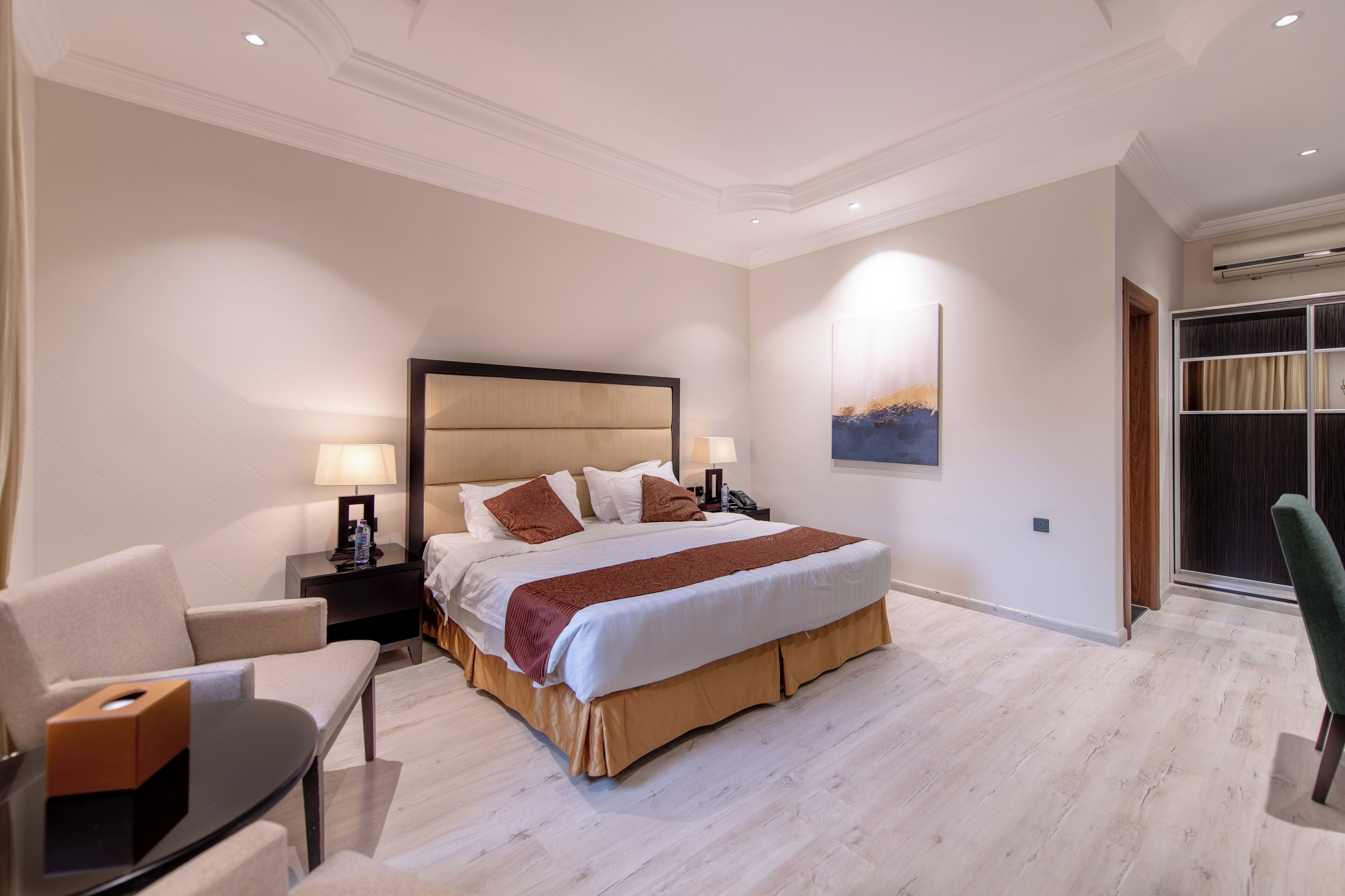 Et moderne hotelværelse med en stor seng, sengeborde med lamper, et skrivebord og en stol.