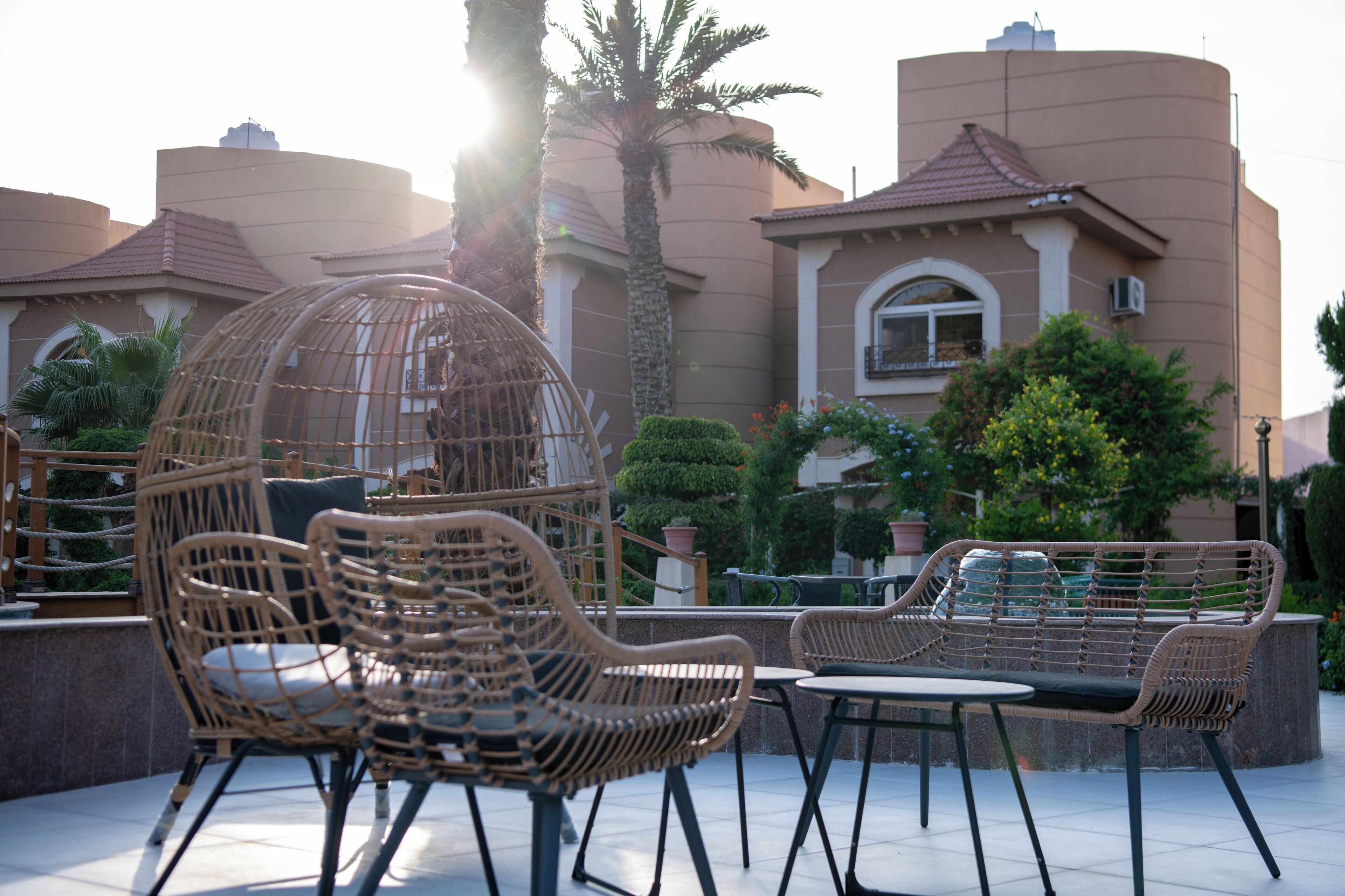 Outdoor wicker furniture, a palm tree, and a building with a curved roof.
