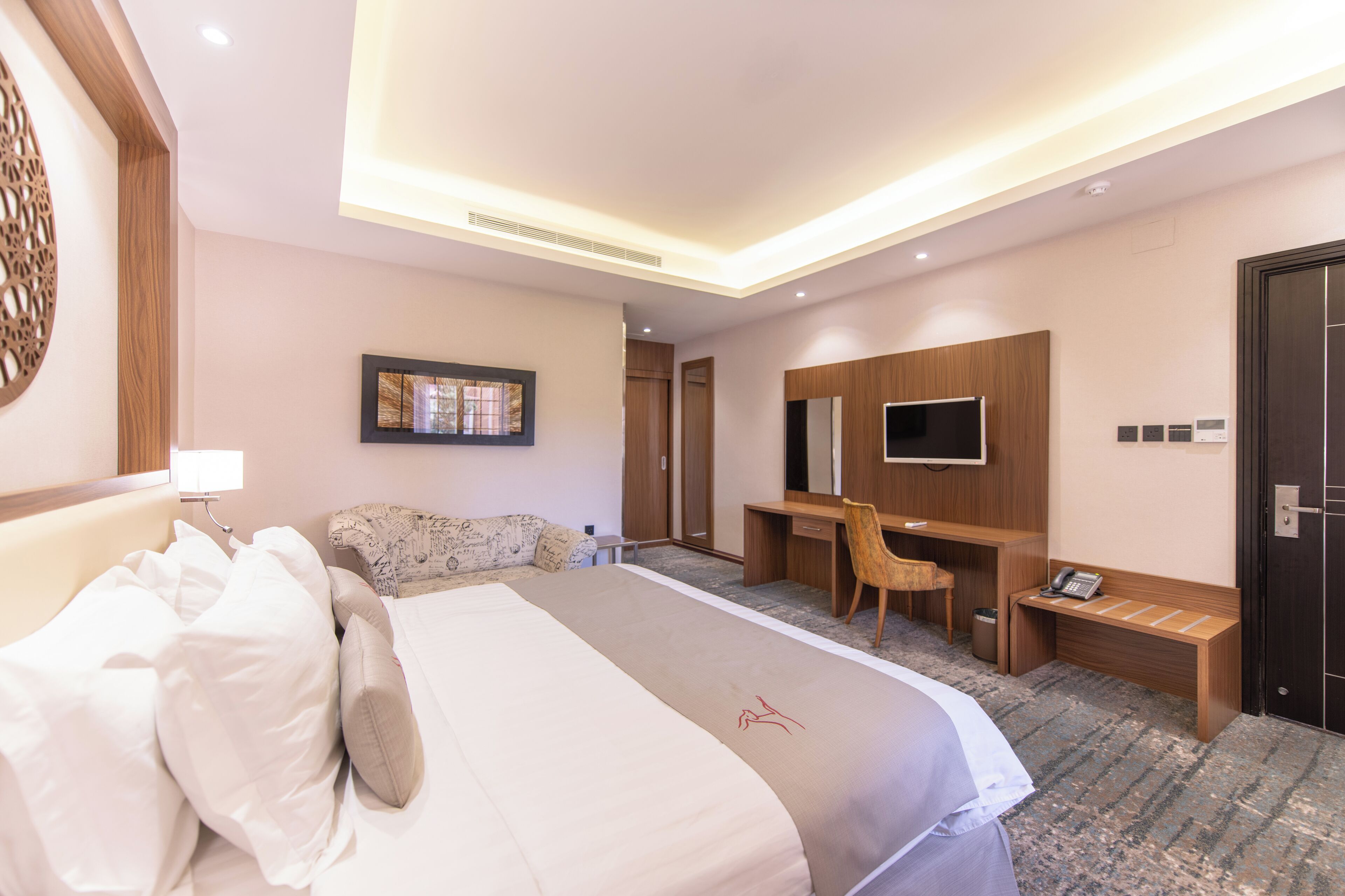 Une chambre d’hôtel avec un grand lit, un bureau, une chaise, une télévision et une armoire.