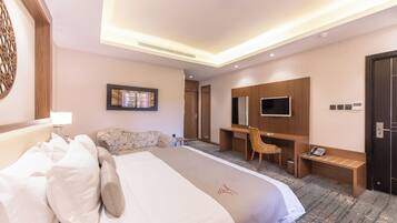 Une chambre d’hôtel avec un grand lit, un bureau, une chaise, une télévision et une armoire.