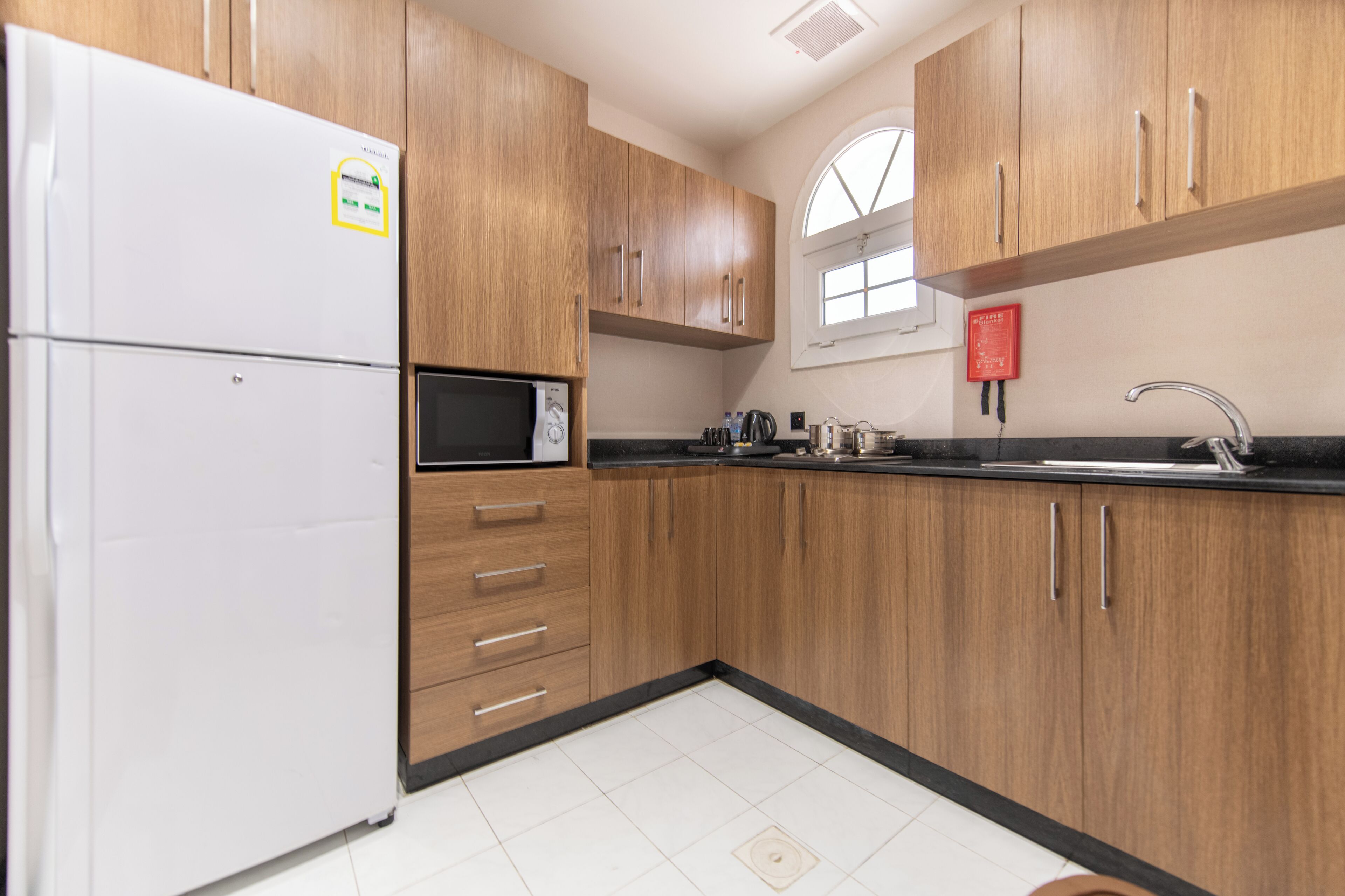 A kitchen with wooden cabinets, a white refrigerator, a microwave, and a sink.