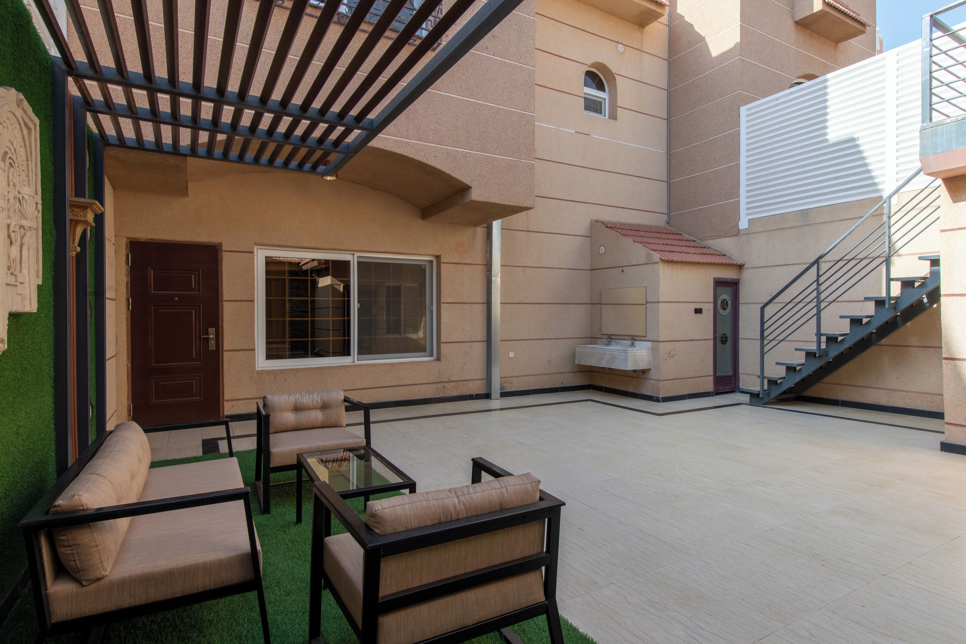 Un área de patio al aire libre con una pérgola, asientos y una escalera.