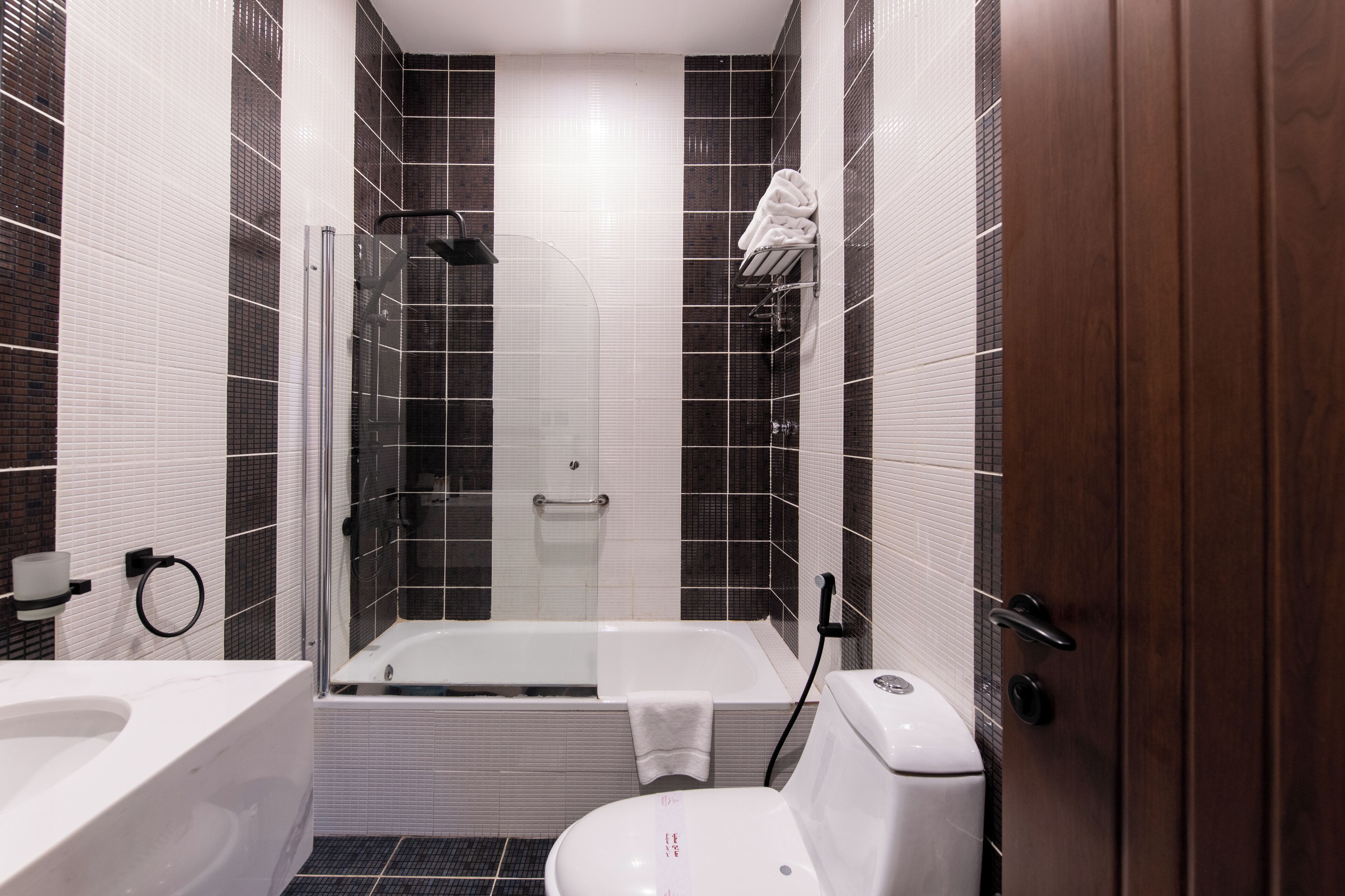 A modern bathroom with a glass-enclosed shower, a white bathtub, and a toilet.