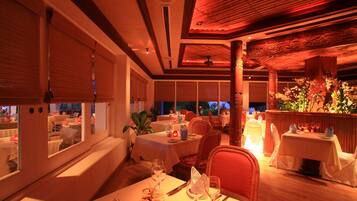 A restaurant with multiple tables set for dining, large windows, and a warm interior ambiance.
