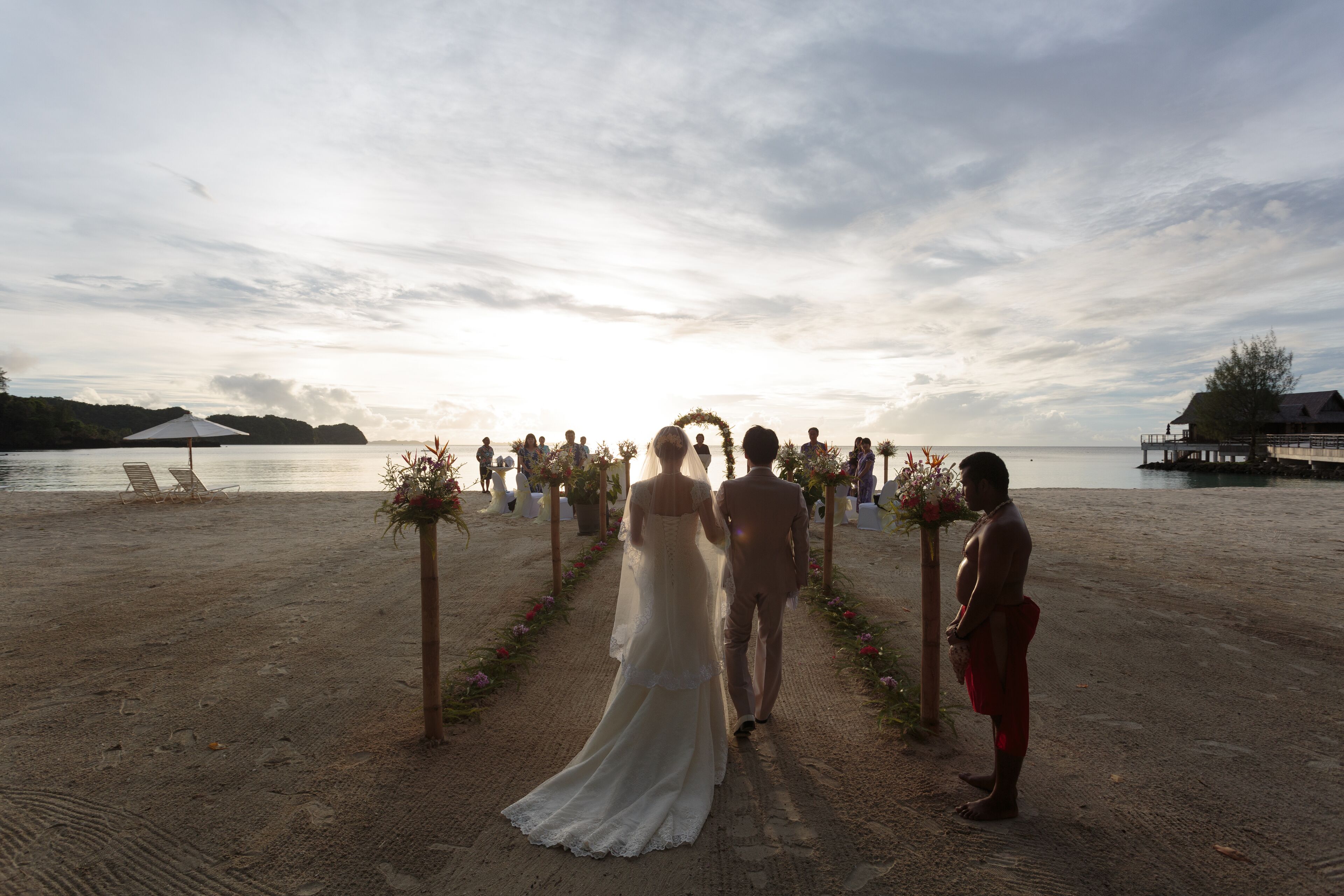 Uma cerimônia de casamento na praia, com céu limpo e mar calmo.