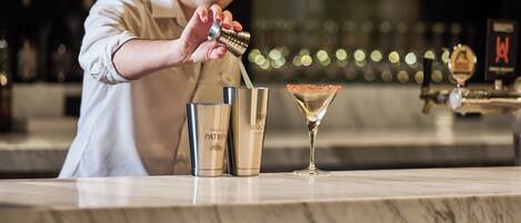 A bartender pouring a drink into a martini glass.
