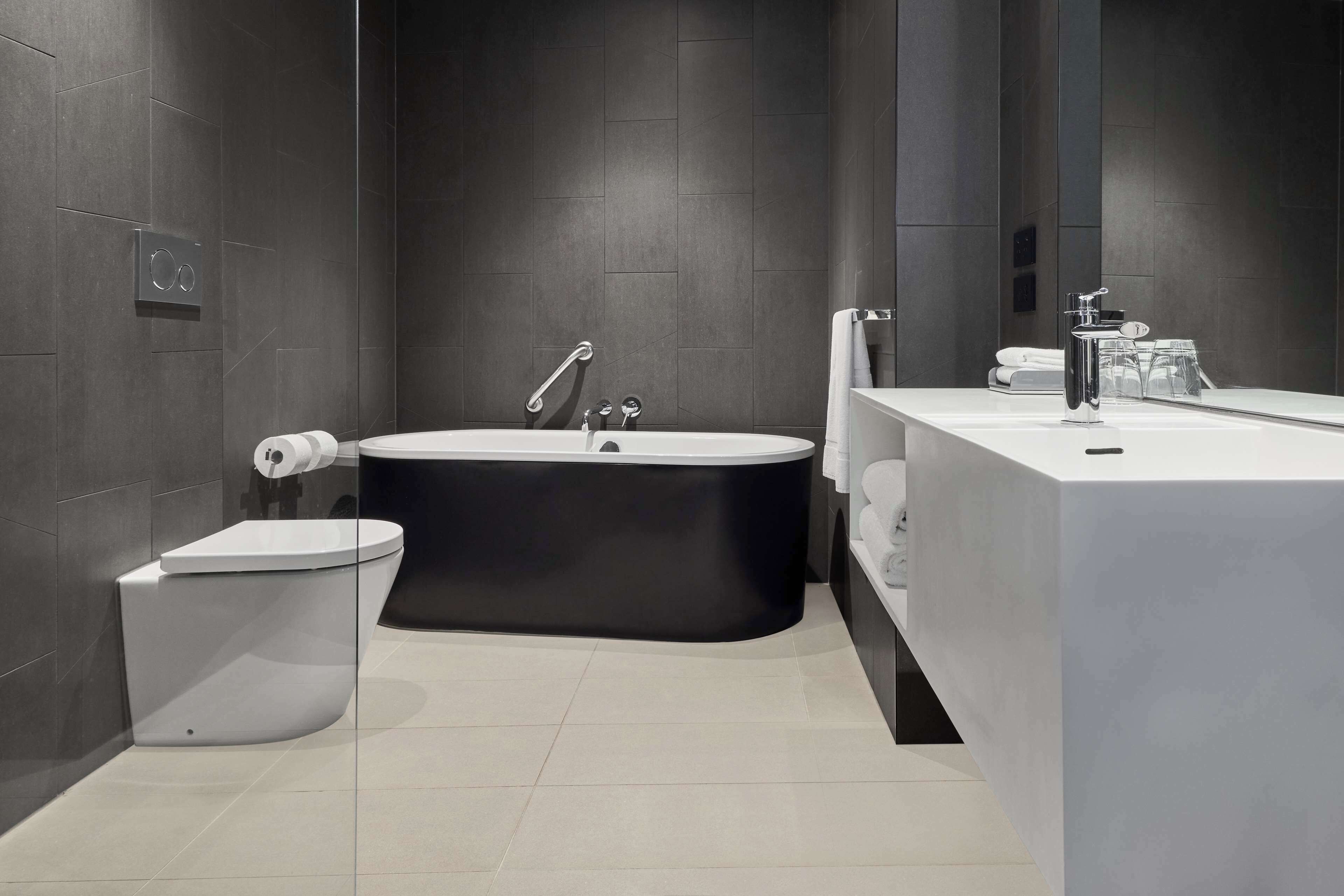 A modern bathroom with a freestanding bathtub, a toilet, and a vanity with a mirror.