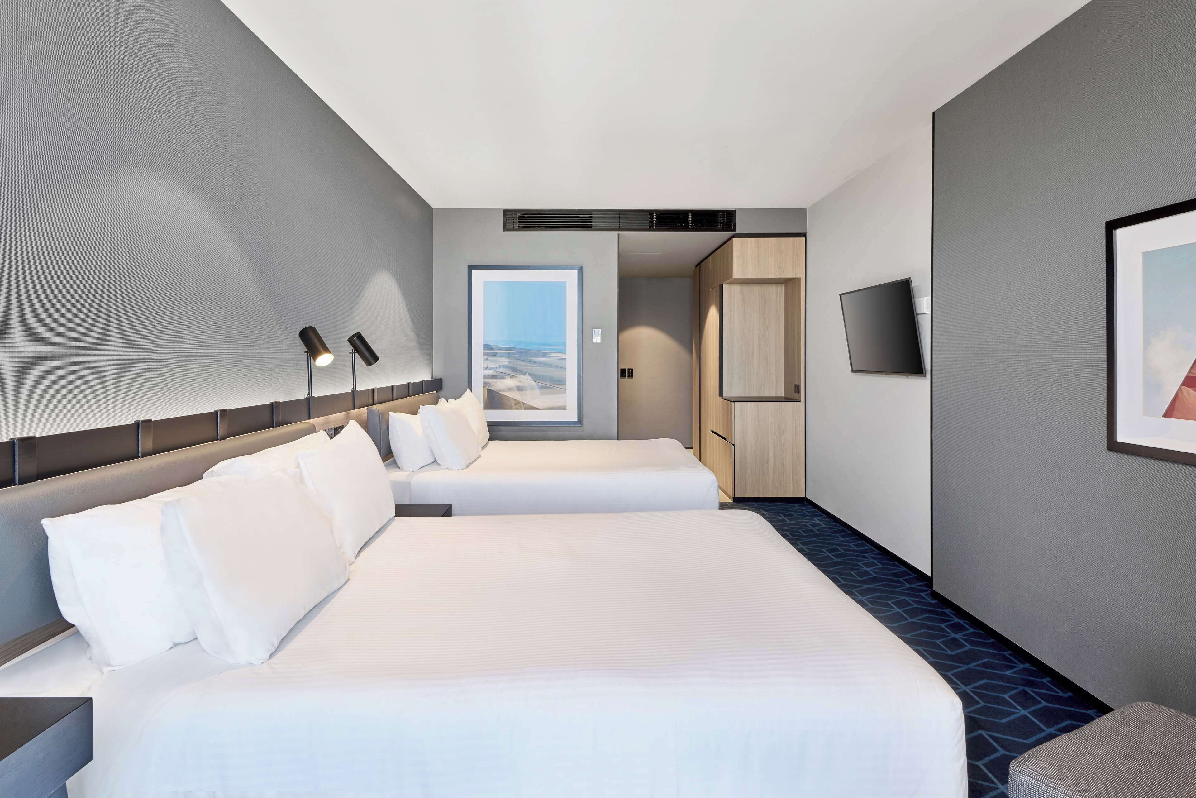 Habitación de hotel con dos camas, televisión y vistas al exterior.