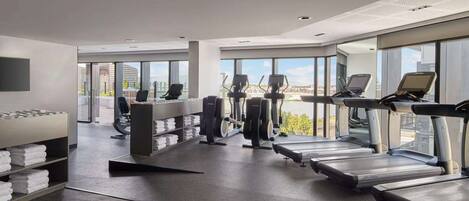 A modern gym with treadmills, elliptical machines, and weight benches.