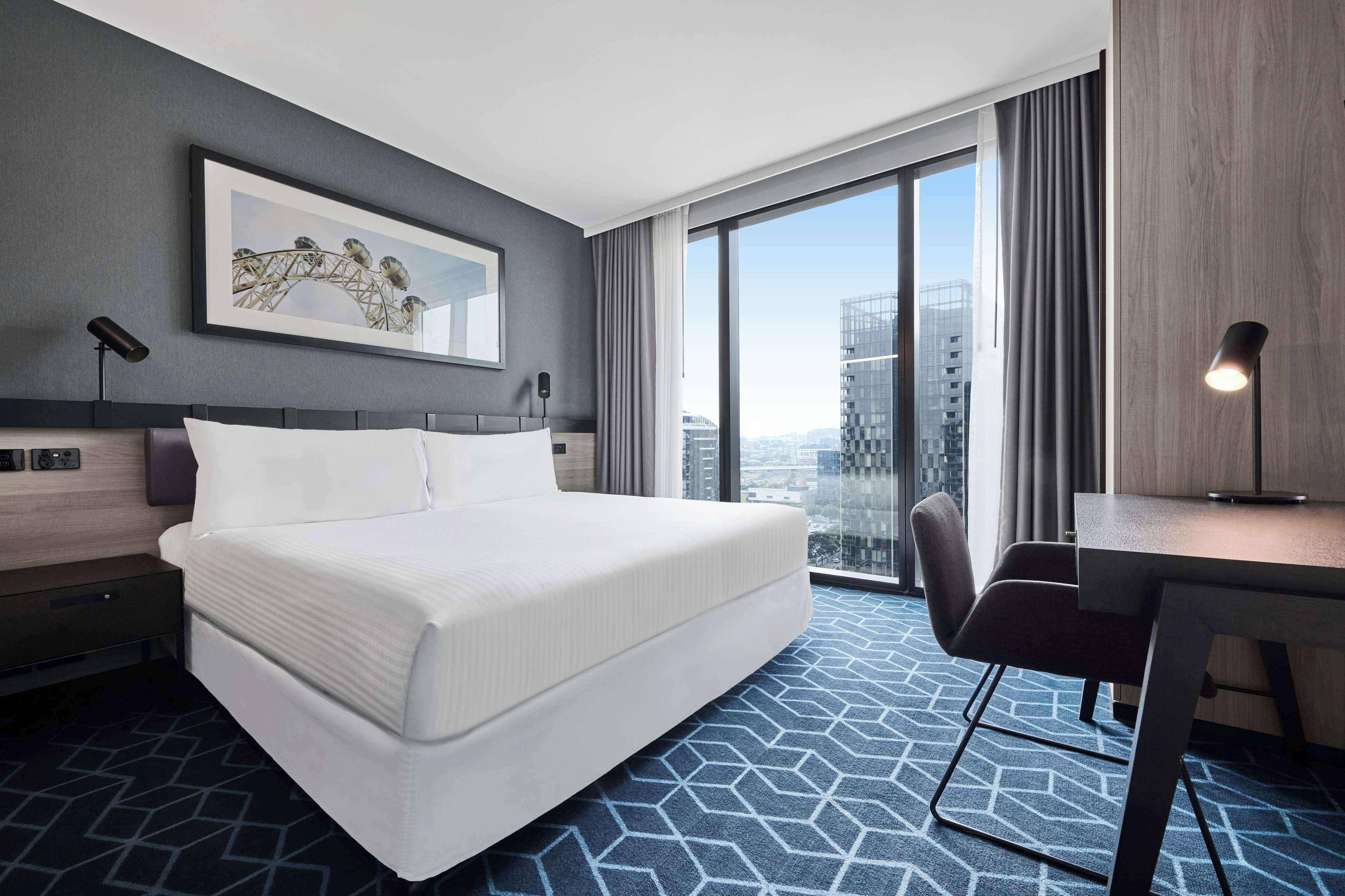 Una habitación de hotel moderna con una cama grande, un escritorio y vistas a la ciudad.