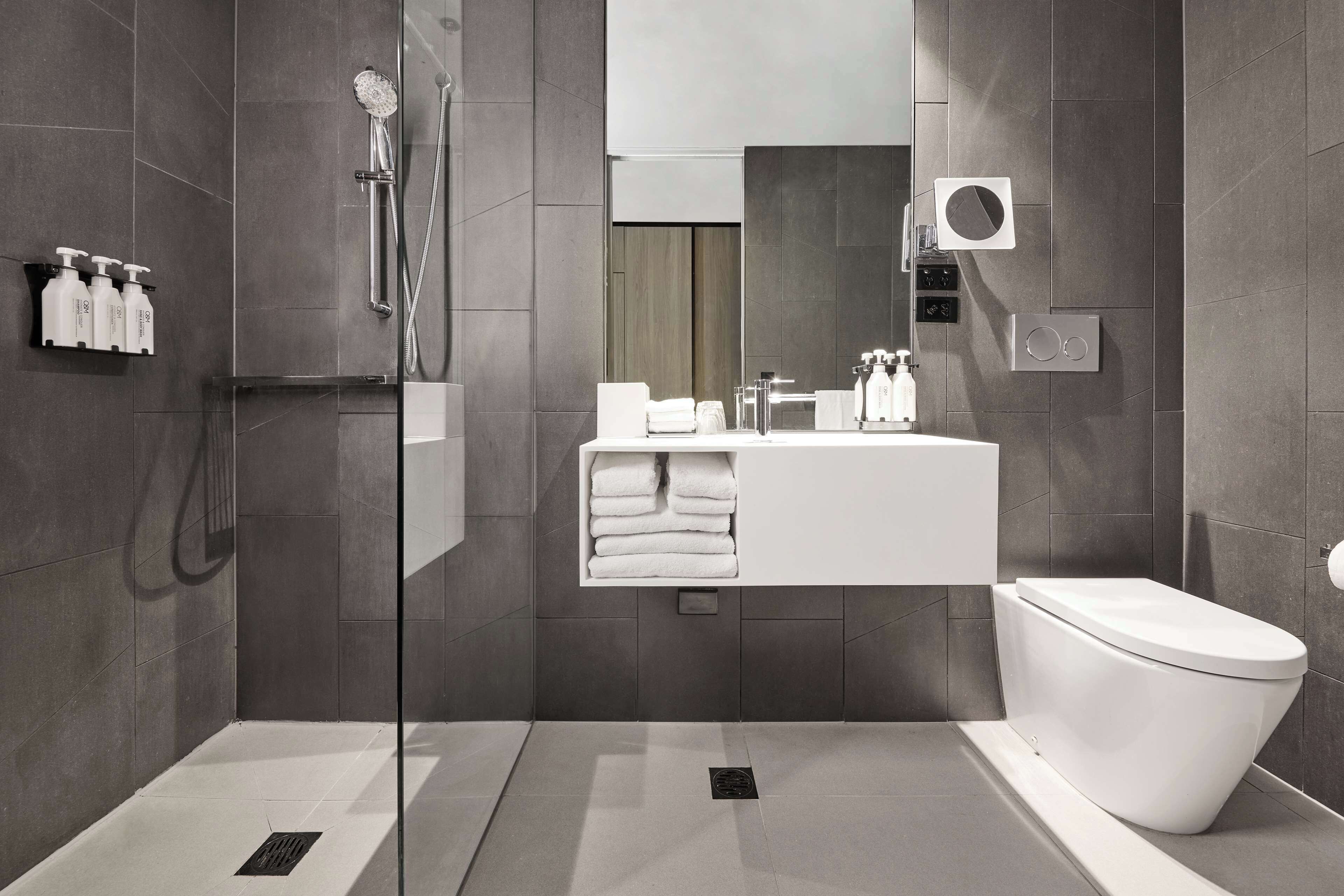 Een moderne badkamer met een glazen douchecabine, een wit wastafelmeubel en een toilet.