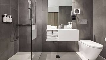 Un baño moderno con ducha acristalada, un lavabo blanco y un inodoro.