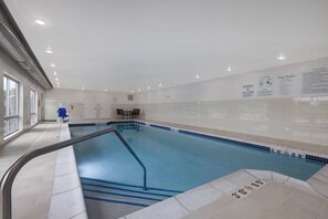 Une piscine intérieure avec des règles d’utilisation claires et des panneaux d’avertissement concernant la sécurité affichés sur les murs, un poste de surveillance pour le sauveteur et un sol carrelé avec des indications de profondeur.