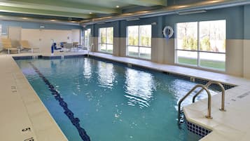 An indoor swimming pool with clear water, marked lanes, and a lifeguard chair.