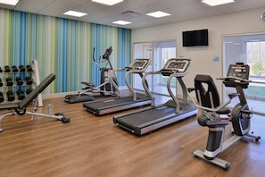 A gym with treadmills, dumbbells, and a television on the wall. - Holiday Inn Express & Suites Brighton South - US 23 by IHG (Brighton)