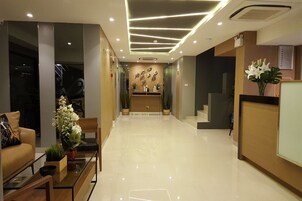Una zona de recepción moderna con piso limpio y pulido, un mostrador de recepción y un área de estar con sofá y mesa de centro.
