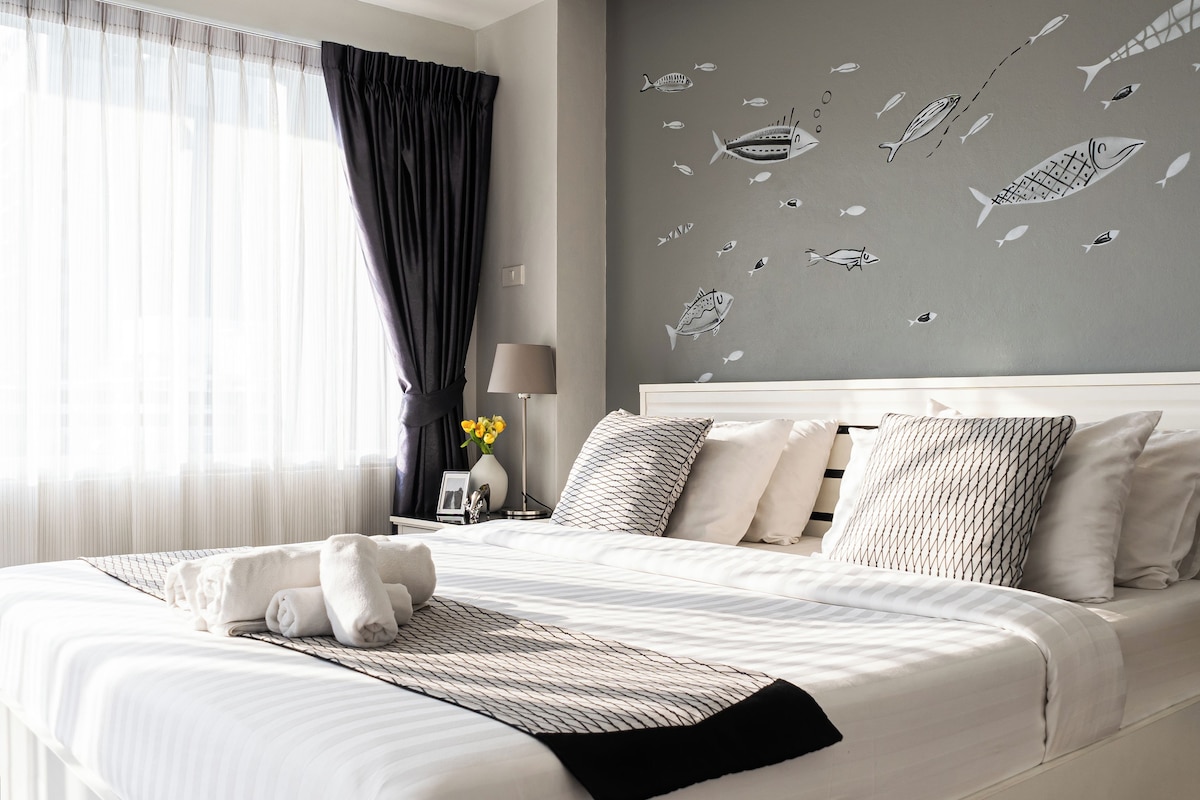 Una camera d'hotel con un letto grande, un comodino con una lampada e una parete decorata con pesci.