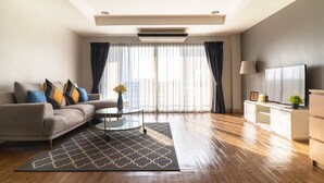 A modern living room with a sofa, a coffee table, and a TV on a stand. - Ploen Place Residence (Pattaya)