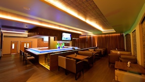 Zona de bar moderna con televisor de pantalla plana, paneles de madera y una barra.