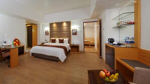 Una habitación de hotel con cama, escritorio, silla y una cesta de fruta.