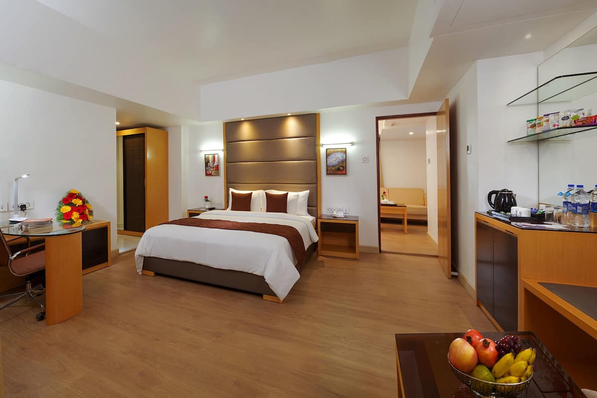 Una habitación de hotel con cama, escritorio, silla y una cesta de fruta.