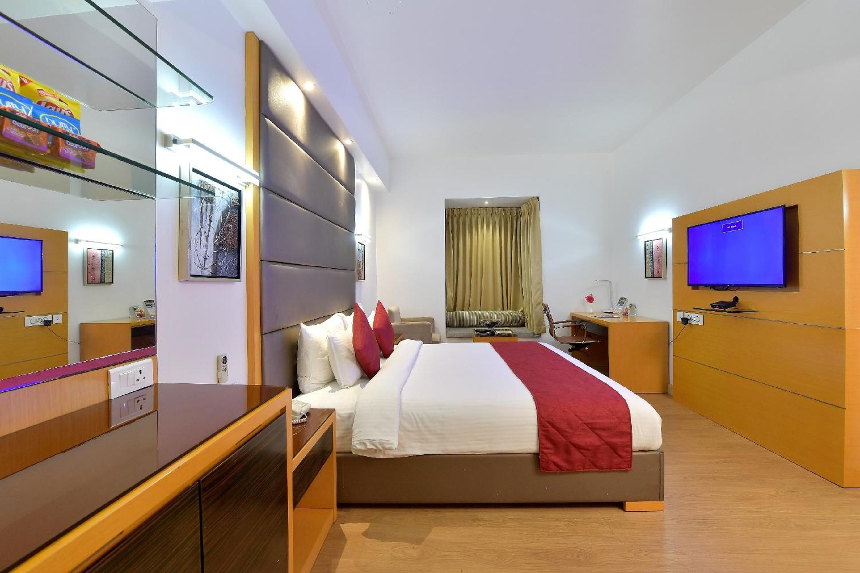 Una habitación de hotel moderna con una cama grande, televisión, escritorio y armario.