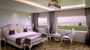 Une chambre d’hôtel avec un grand lit, deux chaises, une petite table et une vue sur la plage.