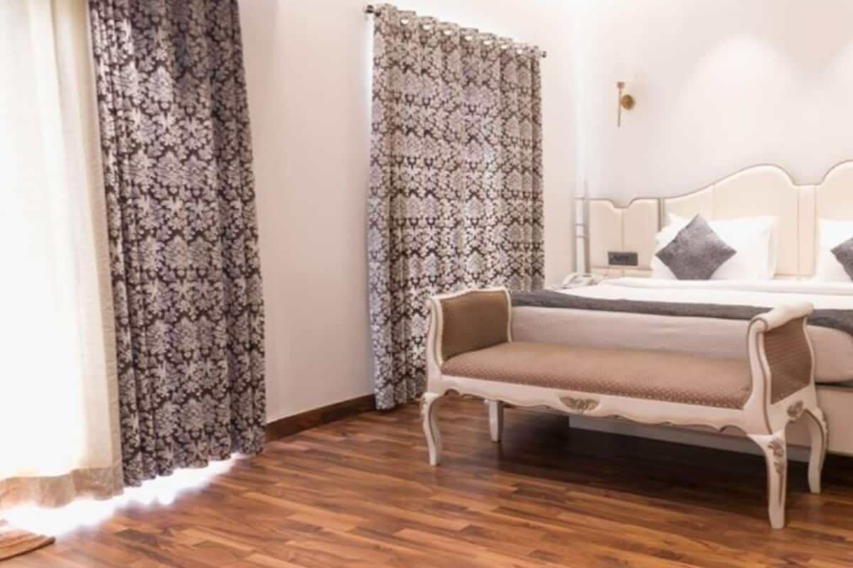 Une chambre à coucher avec un lit, des tables de chevet, un banc et des rideaux à motifs.