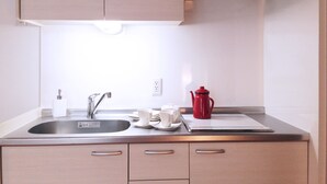 A modern kitchen with a stainless steel sink, a red coffee pot, and a white electric kettle. - Stella Inn Karasuma Gojo (Kyoto)