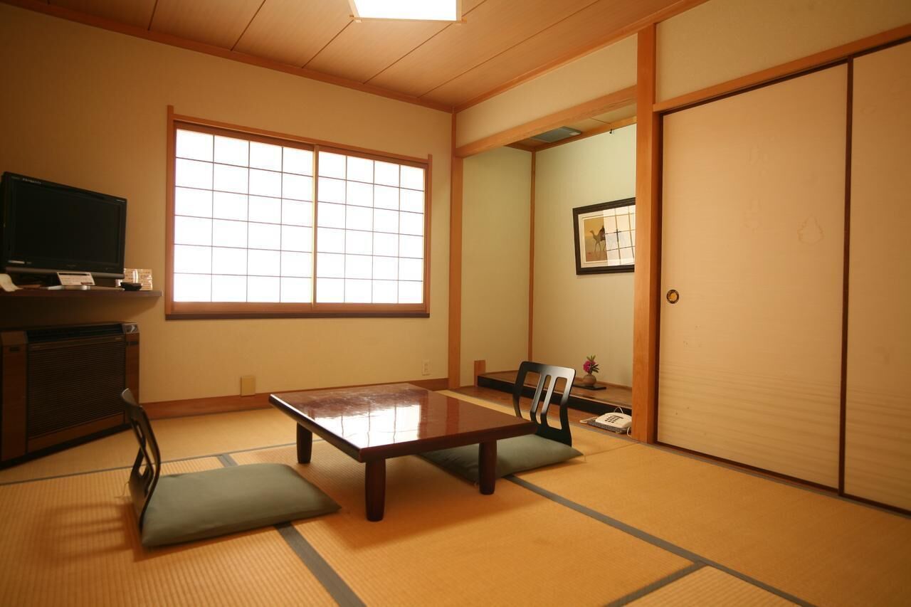 Une pièce de style japonais traditionnel, avec un sol recouvert de tatamis, une table basse et des portes coulissantes.