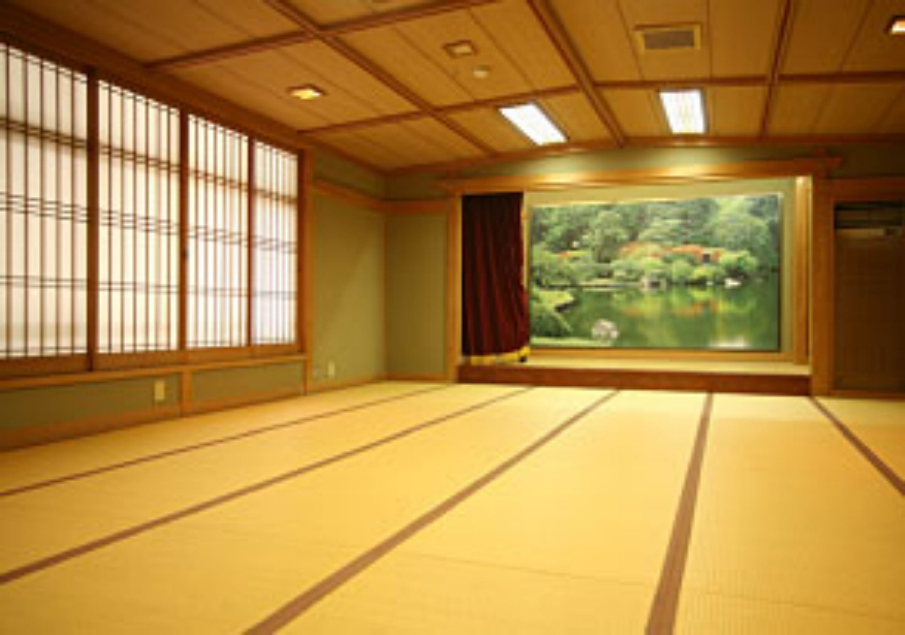 A tatami mat room with a large window, a view of greenery, and a sliding door.