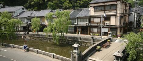 A traditional Japanese building with a stone bridge over a canal, surrounded by greenery.