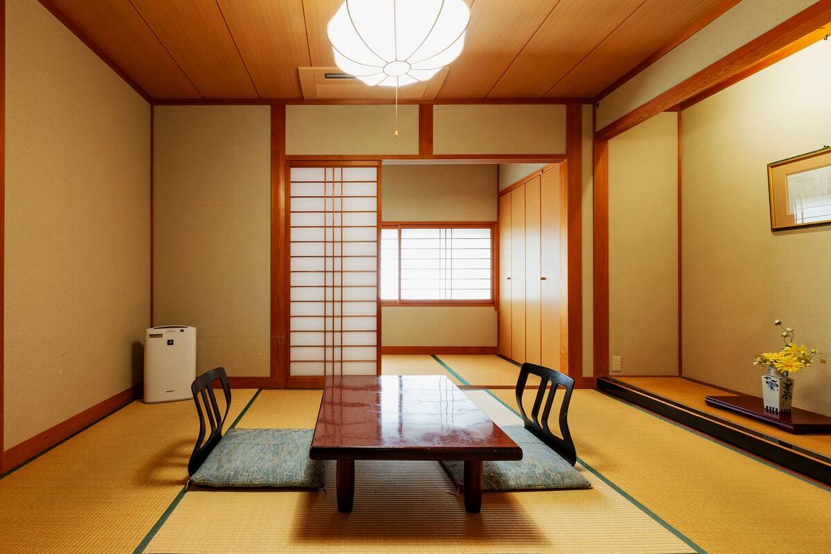 A traditional Japanese room with tatami flooring, a low wooden table, and sliding doors.